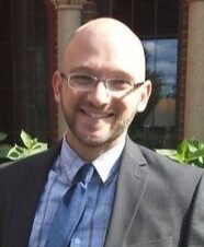 Dr. Stokan in a grey jacket with a white checkered shirt and a blue tie